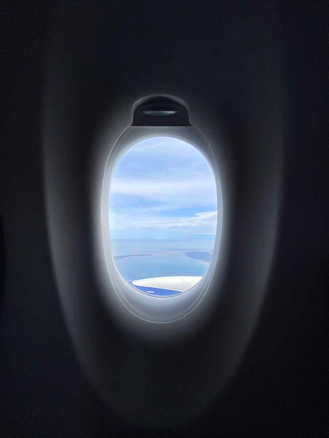 video crew looks outside an airplane window at a beautiful view.